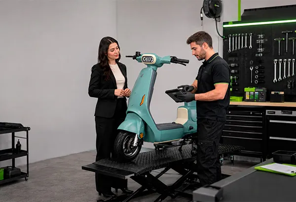 Técnico da e-Hub com luvas revisando uma scooter elétrica no elevador da oficina